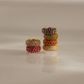 Six Pave Birthstone Charm Spacer rings with colorful gemstones are stacked in two groups on a glossy, beige surface.