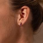 Close-up of a woman’s ear wearing Ombre Blue Zircon Flatback Studs, a small stud earring with three blue zircon stones—ideal as a personalized gift.