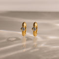 Ribbed Diamond Huggies showcased upright on a reflective, textured surface with soft lighting—an elegant and personalized pair of gold hoop earrings featuring clear gemstones.