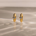 Ribbed Diamond Huggies showcased upright on a reflective, textured surface with soft lighting—an elegant and personalized pair of gold hoop earrings featuring clear gemstones.