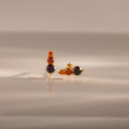 Ombre Garnet Flatback Studs featuring three orange and dark gemstones on a glossy surface with soft lighting—ideal as vibrant earrings or a personalized gift.