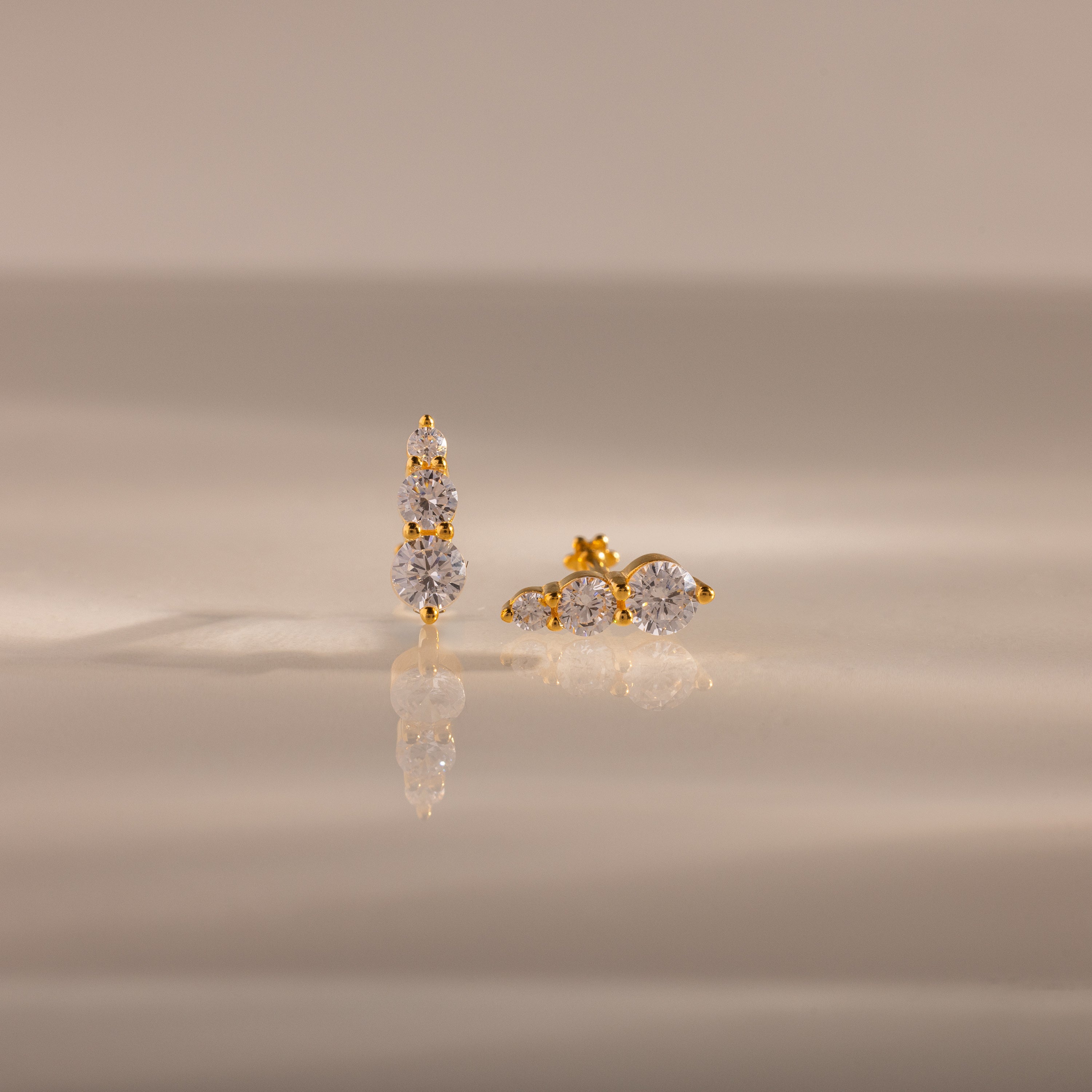 Ombre Diamond Flatback Studs with round, clear gemstones in a vertical design on a neutral surface—these elegant earrings are a perfect personalized gift for any occasion.