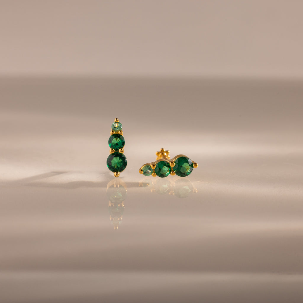 Ombre Emerald Flatback Studs with three round green gemstones on gold, shown on a smooth neutral surface—an elegant pick for fans of personalized jewelry.