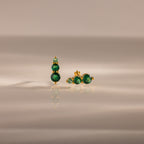 Ombre Emerald Flatback Studs with three round green gemstones on gold, shown on a smooth neutral surface—an elegant pick for fans of personalized jewelry.