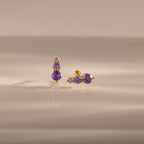 Ombre Alexandrite Flatback Studs with small round purple stones, displayed on a reflective beige surface—a stylish personalized gift ideal for any occasion.