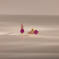 Ombre Pink Tourmaline Flatback Studs feature gold settings with three pink gemstones—one earring vertical, one horizontal—for a striking ombre birthstone effect on a reflective surface.