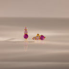 Ombre Pink Tourmaline Flatback Studs feature gold settings with three pink gemstones—one earring vertical, one horizontal—for a striking ombre birthstone effect on a reflective surface.