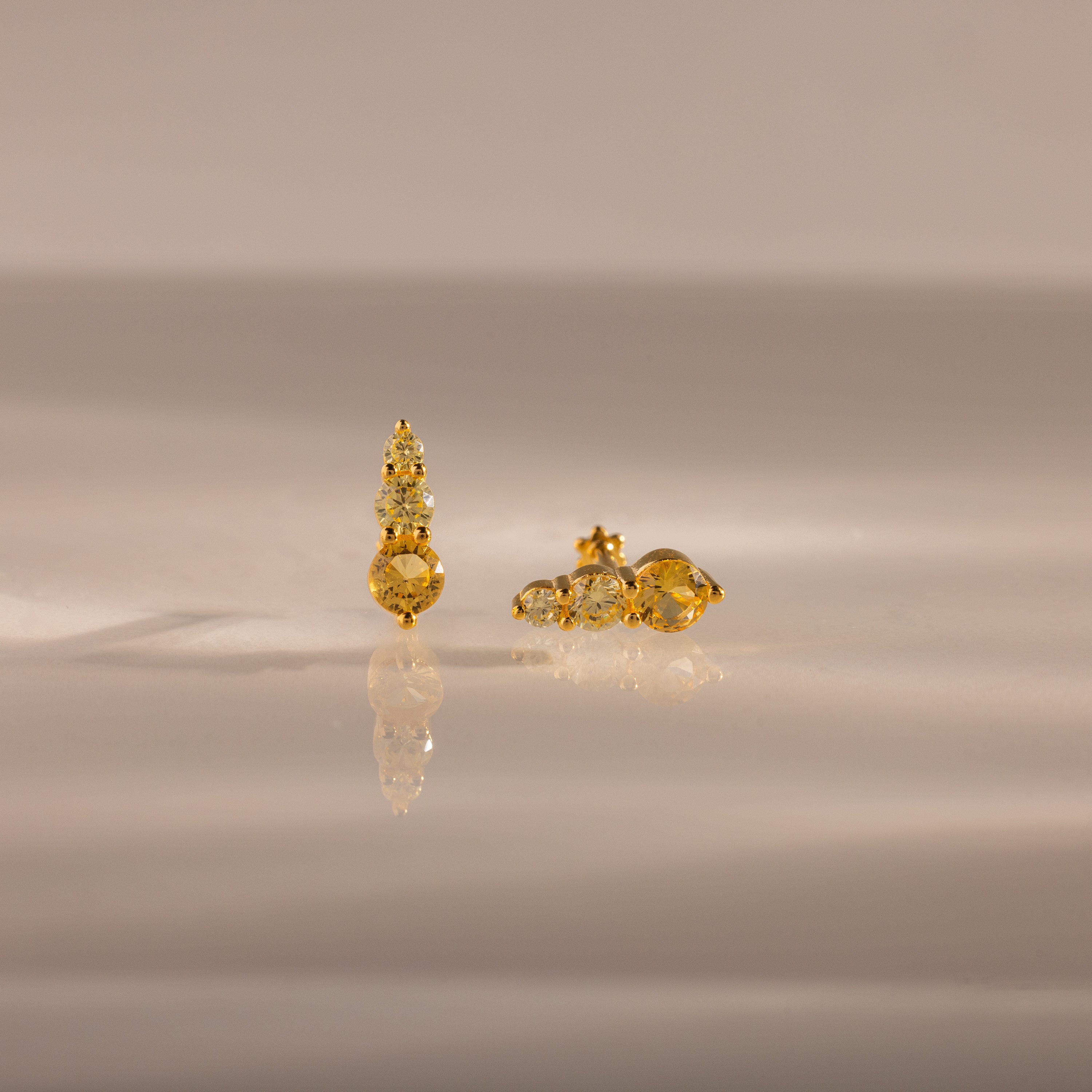 Two gold and diamond Ombre Topaz Flatback Studs are displayed on a smooth, reflective surface with a neutral background.