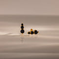 Ombre Onyx Flatback Studs featuring three round black stones on a gold setting, displayed on a smooth, reflective surface—a perfect personalized gift.