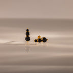 Ombre Onyx Flatback Studs featuring three round black stones on a gold setting, displayed on a smooth, reflective surface—a perfect personalized gift.