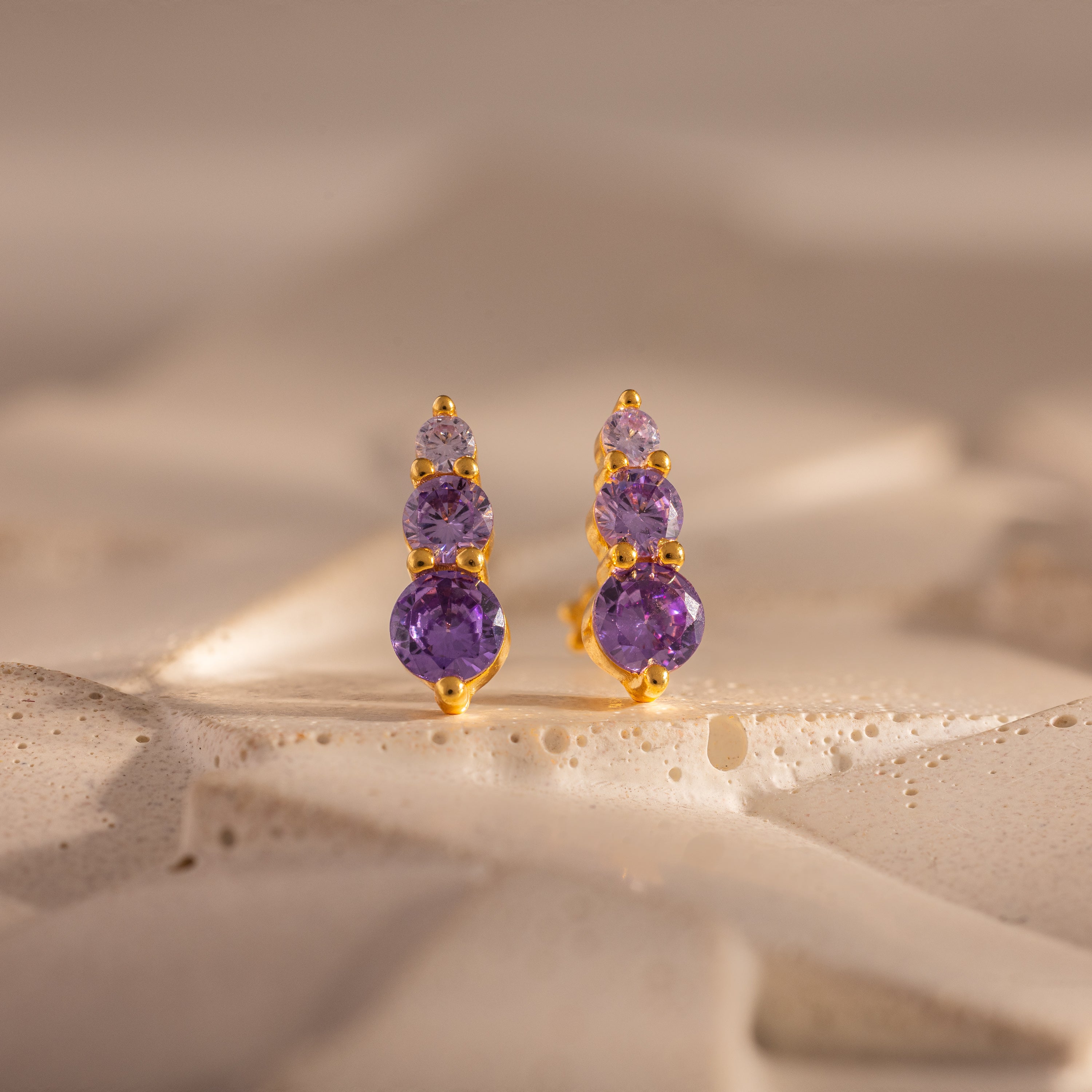 Ombre Alexandrite Flatback Studs with three purple gemstones, shown on a textured light surface—perfect as a personalized gift or stylish studs.