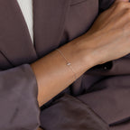 Model wearing a dainty silver bubble initial charm bracelet with the letter S.