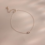 The Bubble Initial Bracelet is a delicate silver personalized piece featuring an initial charm, ideal for everyday wear and beautifully displayed on a light beige surface.