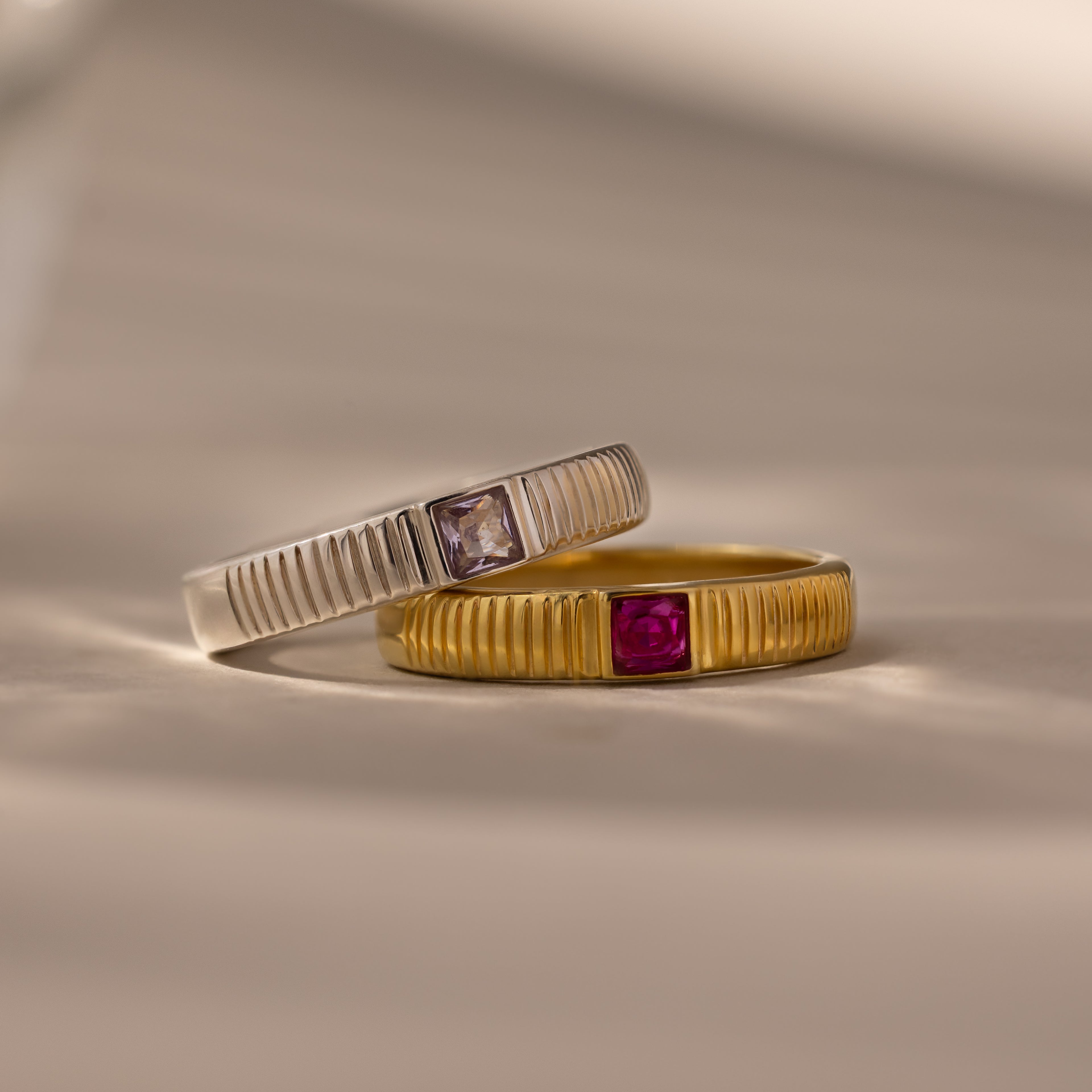 The Ribbed Alexandrite Band, a ribbed ring featuring a lab-created alexandrite stone, is displayed on a neutral background.