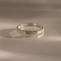 The Ribbed Name Ring in Silver, engraved with Mama, Noah, and Emma, is shown on a neutral background.