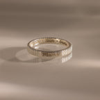 The Ribbed Name Ring in Silver, engraved with Mama, Noah, and Emma, is shown on a neutral background.