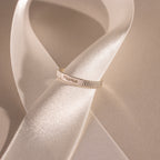A silver Ribbed Name Ring engraved with Mama rests on a white satin ribbon.