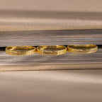 Three Ribbed Name Rings, each engraved with a custom name, rest on the edge of a closed, textured book.
