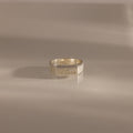A Ribbed Name Signet Ring in Silver, engraved with the name Anna, rests on a smooth, light surface.