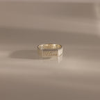 A Ribbed Name Signet Ring in Silver, engraved with the name Anna, rests on a smooth, light surface.