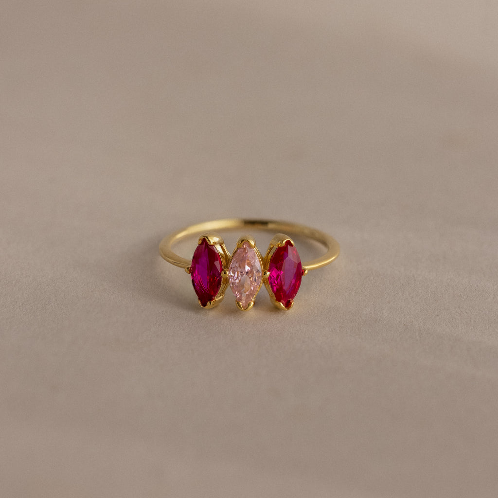 Multiple Marquise Birthstone Ring in 18K Gold features three marquise stones—two red flanking a pink—set on a beige background, making it an elegant, personalized addition to your jewelry collection.