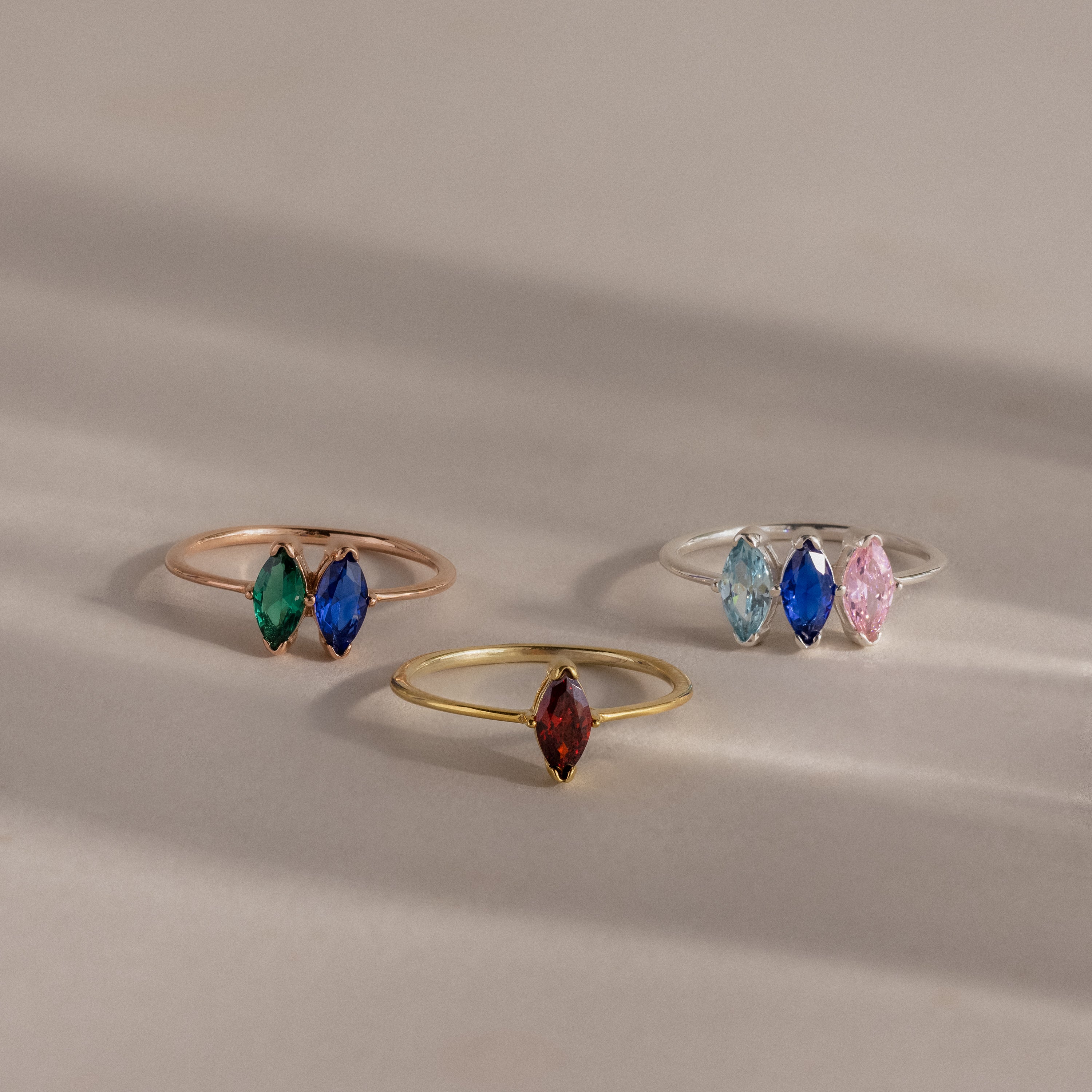 The Multiple Marquise Birthstone Ring features three delicate marquise-cut stones in different colors, beautifully displayed on a neutral background.