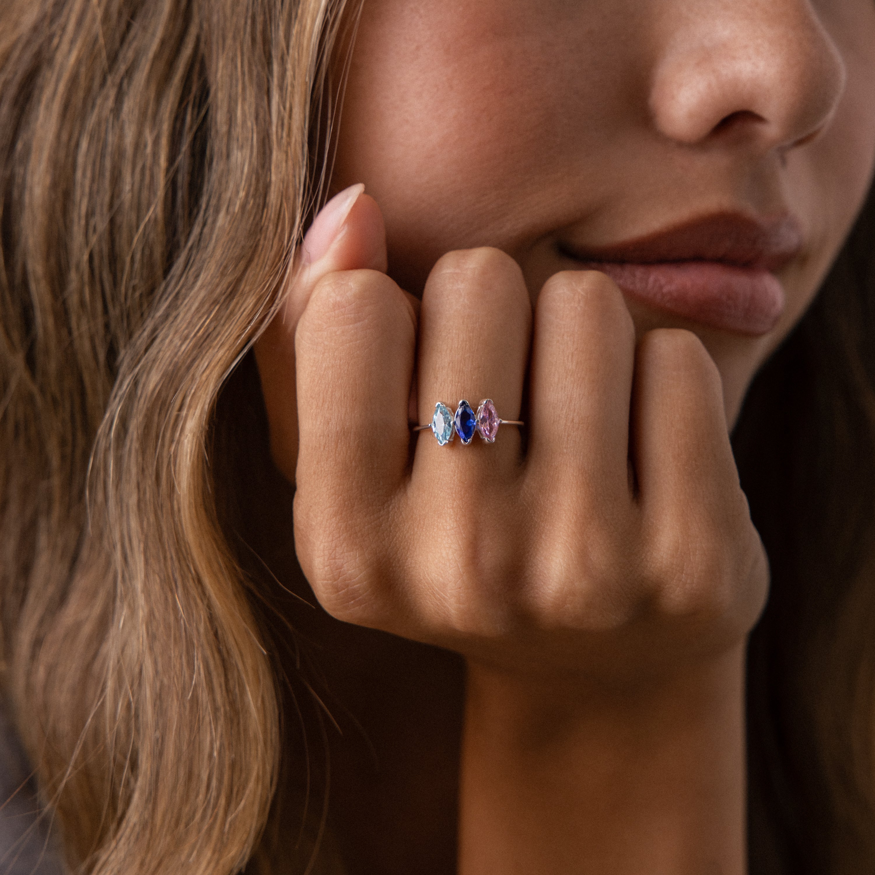 Woman resting her chin on her hand, displaying the Multiple Marquise Birthstone Ring in Sterling Silver—a striking personalized jewelry piece with three vibrant gemstones, ideal for milestone gifts.