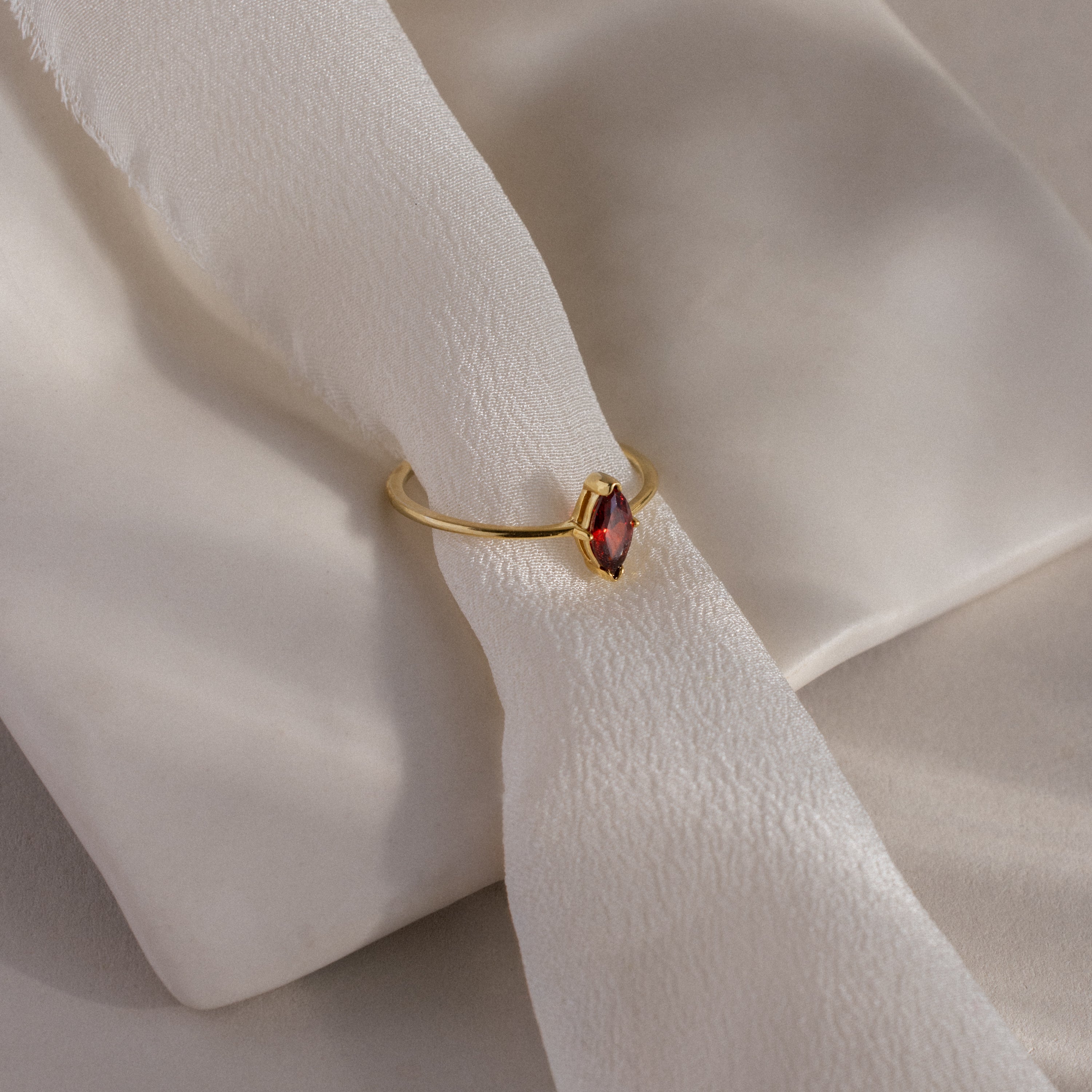 The Multiple Marquise Birthstone Ring features elegant marquise-cut stones set in gold, beautifully displayed on a soft, white textured fabric—an exquisite personalized birthstone ring.