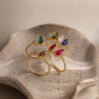The Multiple Marquise Birthstone Rings in 18K Gold, including a personalized birthstone option, are displayed on a speckled ceramic dish.