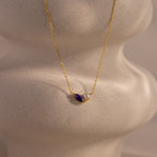 The Marquise Amethyst & Pearl Necklace is a gold piece featuring a purple marquise amethyst birthstone and a pearl pendant, shown on a white, textured display bust.