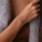 The Toi et Moi Teardrop Heart Bracelet in Rose Gold adorns a woman's wrist, styled with a brown top and gray fuzzy sweater.