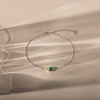 The Toi et Moi Teardrop Heart Bracelet in Sterling Silver features yellow and green gemstones, displayed on a neutral background with soft shadows.