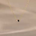 The Teardrop Onyx & Pearl Necklace features a gold chain with a delicate white pearl and black teardrop onyx pendant, displayed on a neutral beige background—an elegant, timeless gift for any occasion.