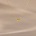 The Teardrop Topaz & Pearl Necklace features a gold chain with a small pearl and yellow topaz teardrop pendant, beautifully displayed on a neutral background—a timeless gift for any occasion.