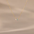 The Teardrop Aquamarine & Pearl Necklace features a small pearl and light blue aquamarine pendant, making it a perfect gift for milestones. Presented against a beige background.