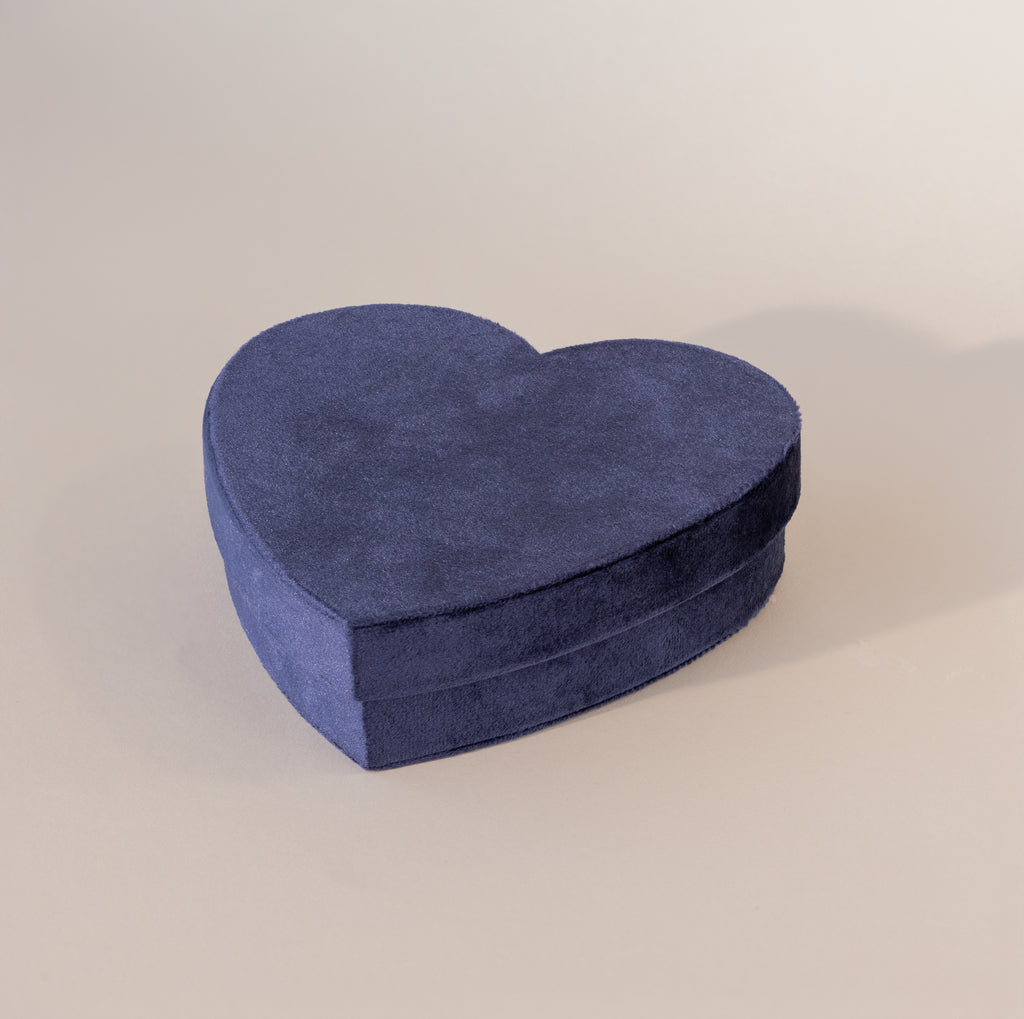 Closed blue velvet heart-shaped jewelry box with soft texture, displayed on a neutral background.