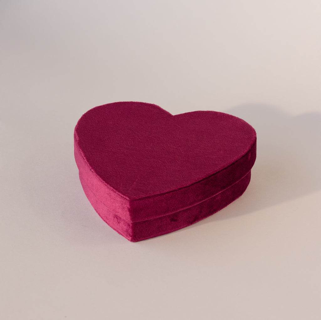 Closed red velvet heart-shaped jewelry box with soft texture, displayed on a neutral background.