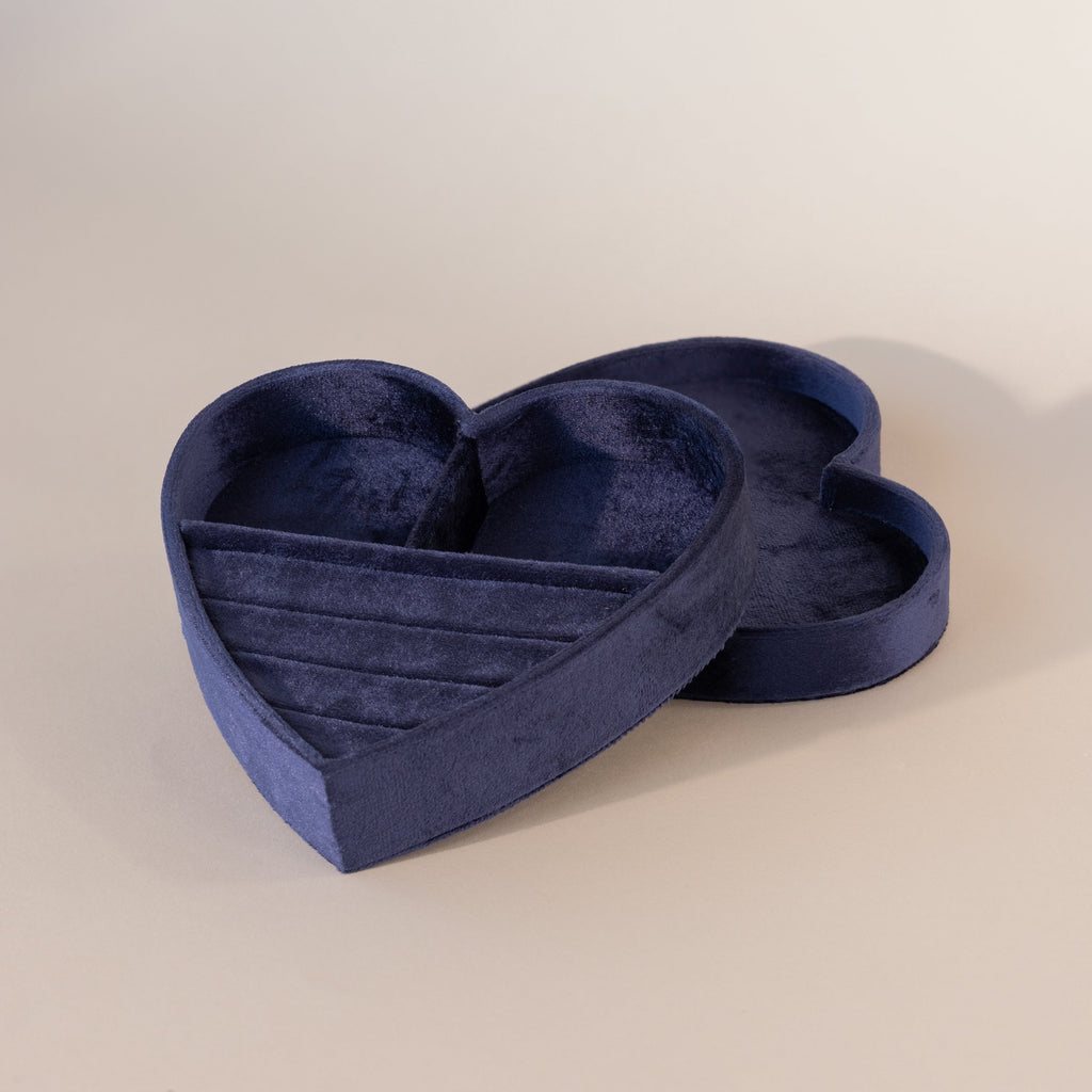 Blue velvet heart-shaped jewelry box with lid, featuring ring slots and compartments on a neutral background.