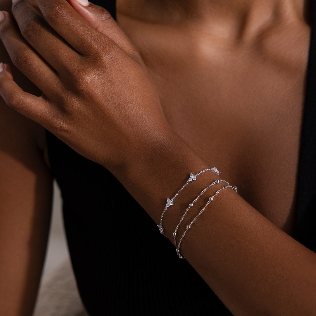Close-up of a person's wrist wearing two silver bracelets on a dark background