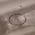 Silver beaded bracelet on a beige fabric background
