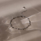 Silver beaded bracelet on a beige fabric background