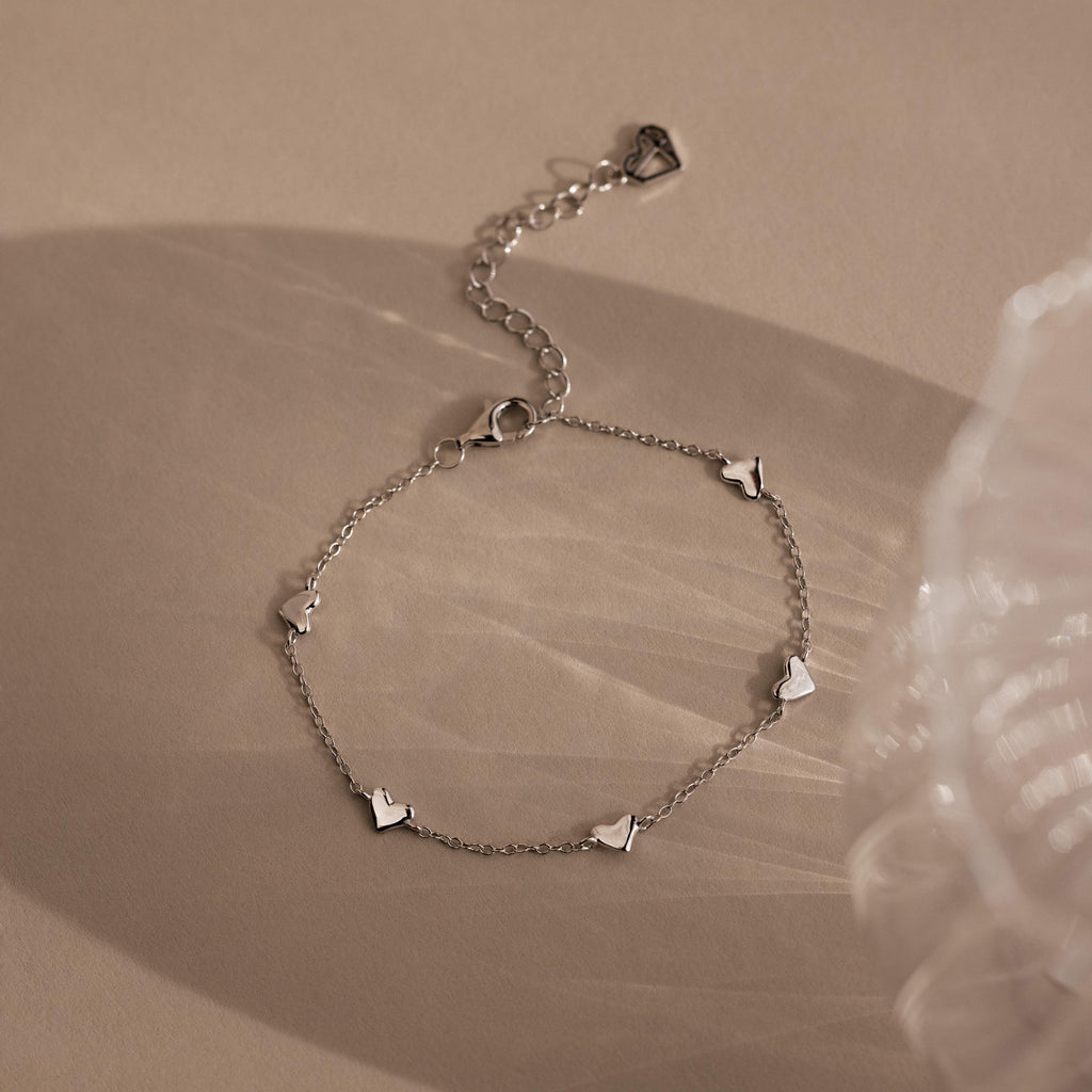 Heart Station Bracelet in Sterling Silver with small heart charms on a soft, neutral backdrop—a romantic, versatile piece and perfect stackable bracelet for any occasion.