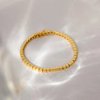 The Cube Bracelet features geometric bead links and rests on a light, reflective surface, casting soft shadows—a bold men's statement jewelry piece.