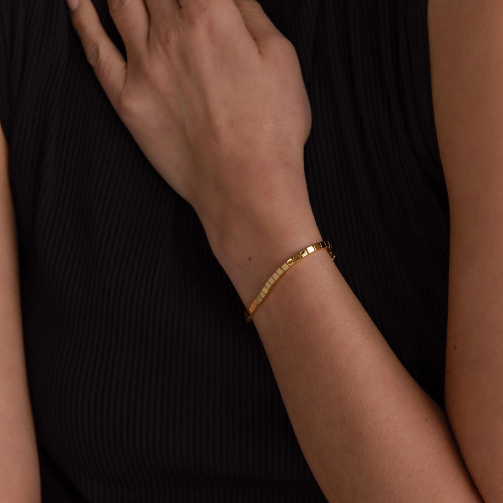 Someone wearing a Cube Bracelet with geometric bead links on their wrist, styled with a sleeveless black top.