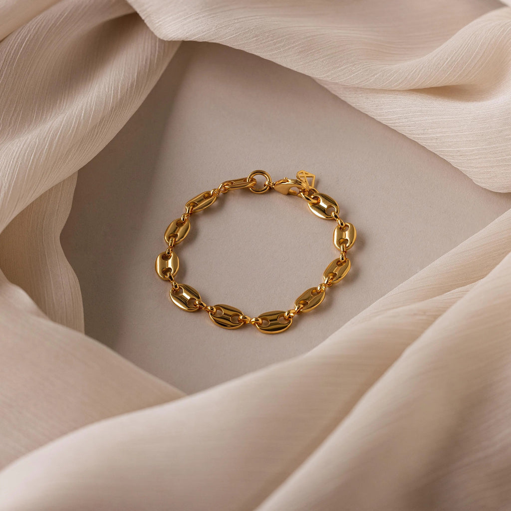 The Bold Mariner Chain Bracelet, featuring oversized links, is showcased on a softly folded neutral fabric background, highlighting its refined statement jewelry style.