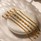 A Bold Mariner Chain Bracelet is displayed on a smooth stone surface in soft sunlight, highlighting its striking gold design.