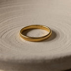 The Thick Snake Chain Bangle, featuring a bold ribbed design, is displayed on a light, textured surface.