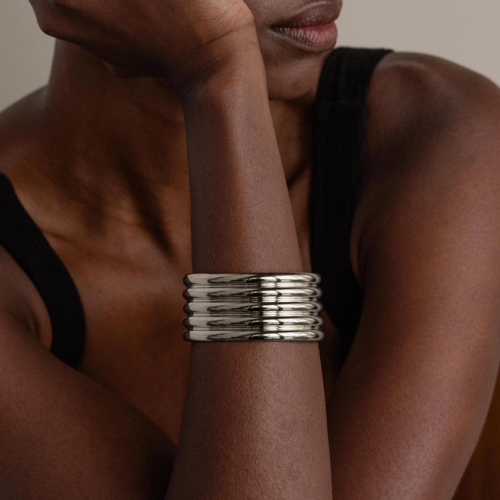 A person wearing a sleeveless black top and the Ribbed Cuff Bracelet on their wrist.