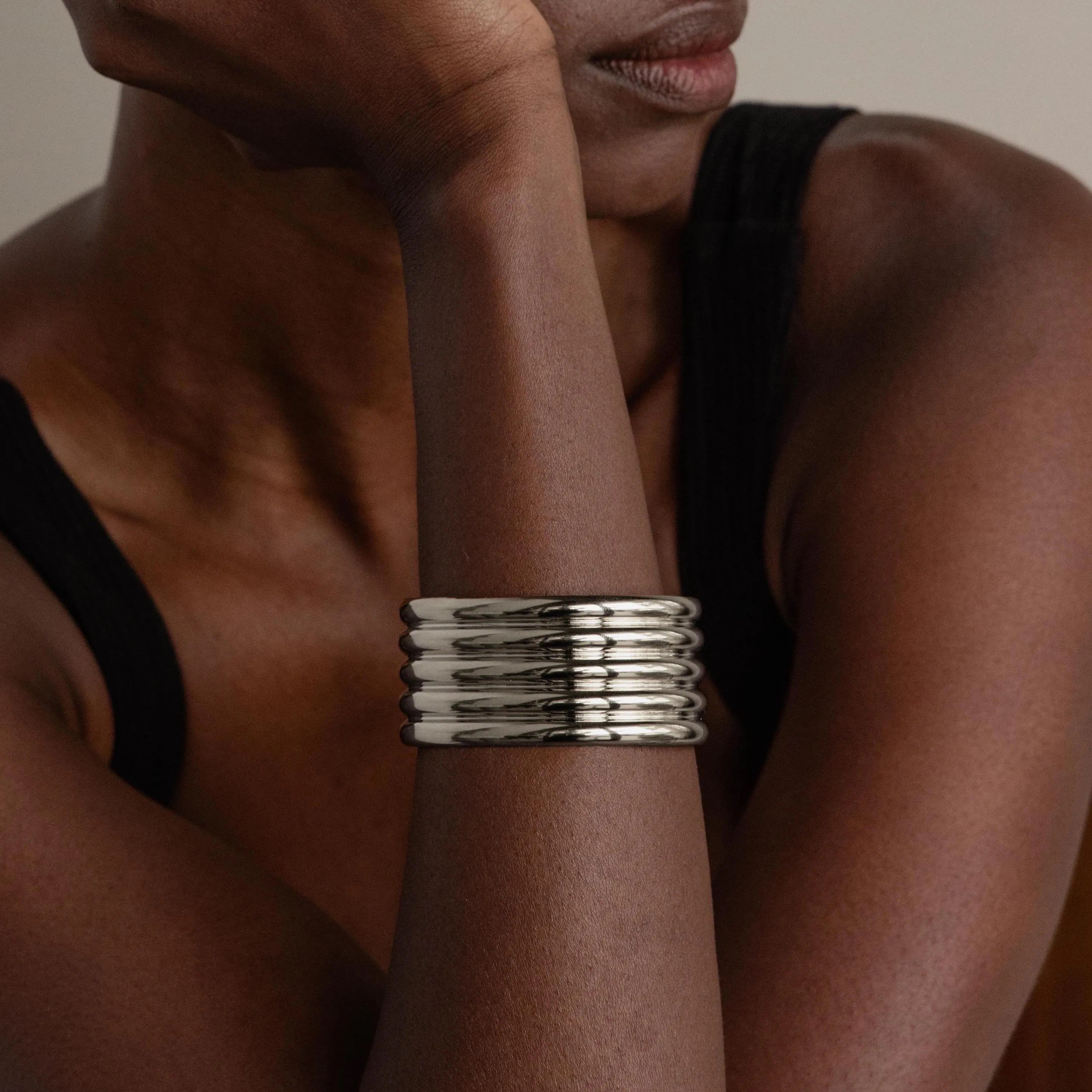 A person wearing a sleeveless black top and the Ribbed Cuff Bracelet on their wrist.