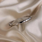 Close up flat lay of silver North Star Diamond Bangle Bracelet resting on soft ivory fabric